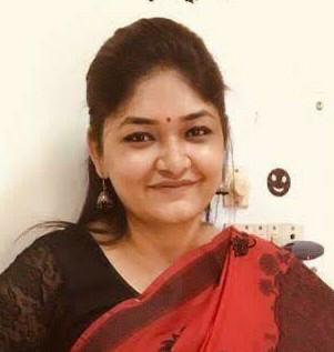 A businesswoman sitting at her desk, smiling and looking at the camera.