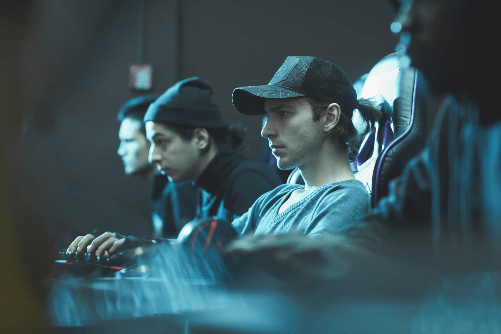 A group of esports players sitting in gaming chairs, focused on their computers during a competitive gaming session or tournament.
