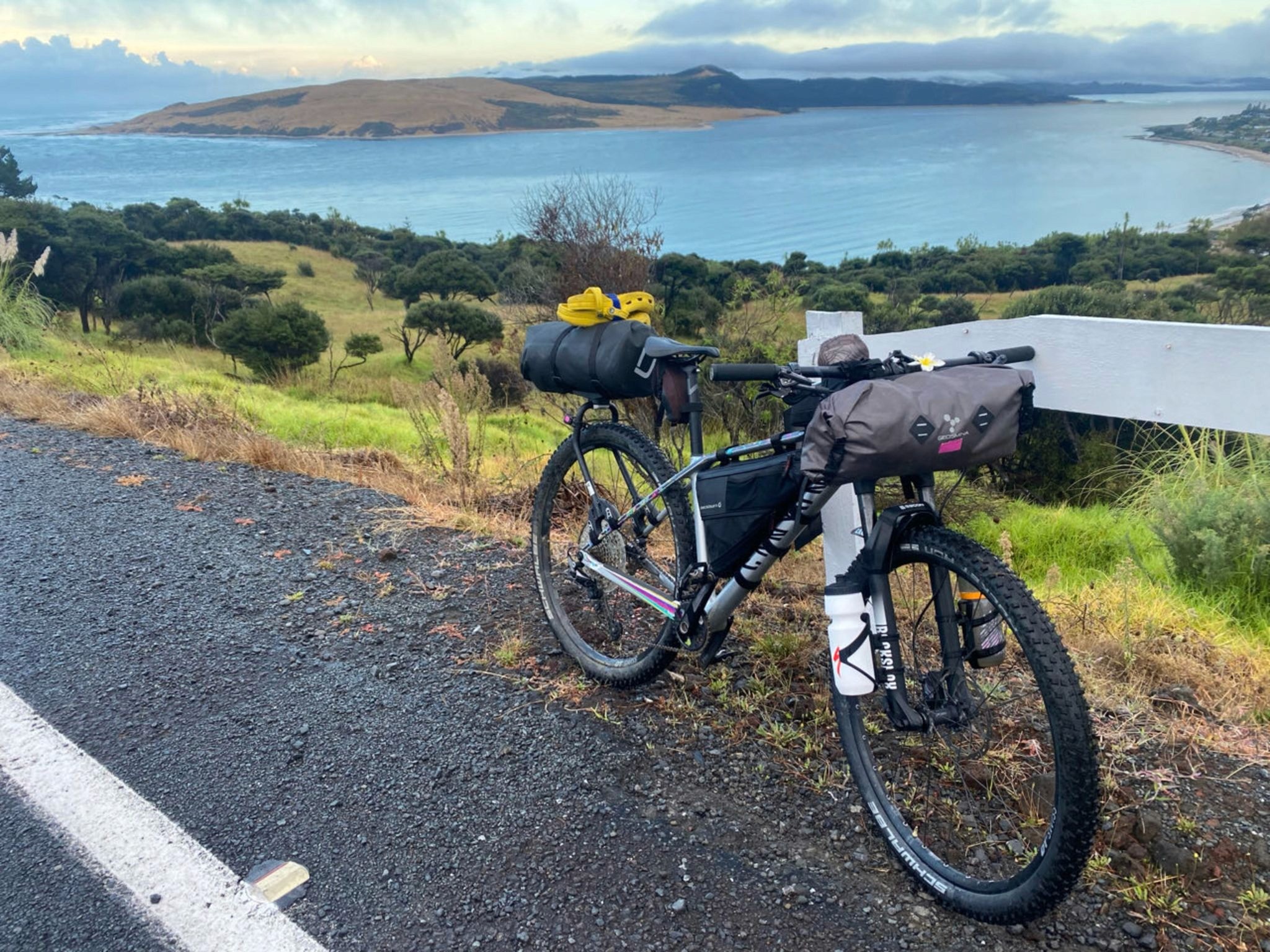 A bike parked at the side of road in New Zealand with the sea and distant islands in the background