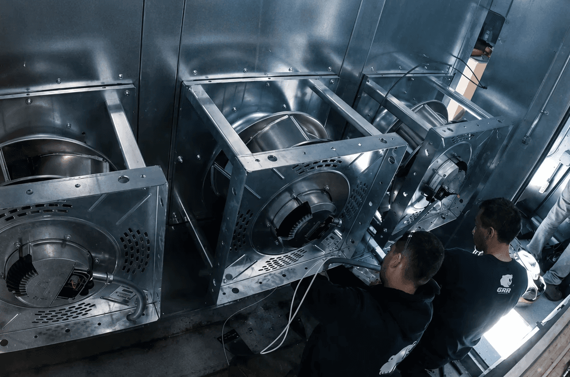 GRR Cooling Experts technicians installing and commissioning an HVAC fan array inside a commercial air handling unit in New York City.