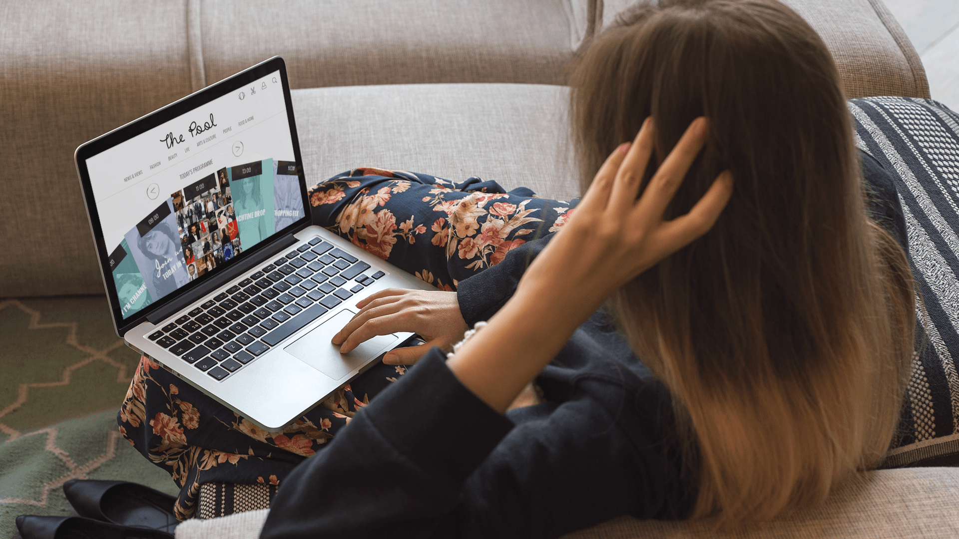 A woman on a couch browsing The Pool's website