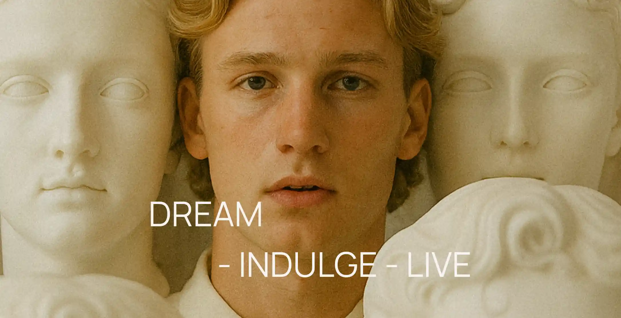 A serene portrait of a young man framed by classical marble sculptures — a blend of human warmth and timeless artistry, evoking elegance, introspection, and the essence of living beautifully.