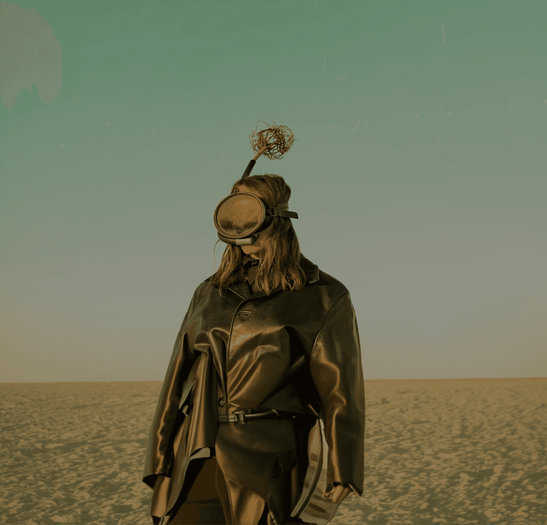 A person wearing a mask with an antenna standing against a pale sky.
