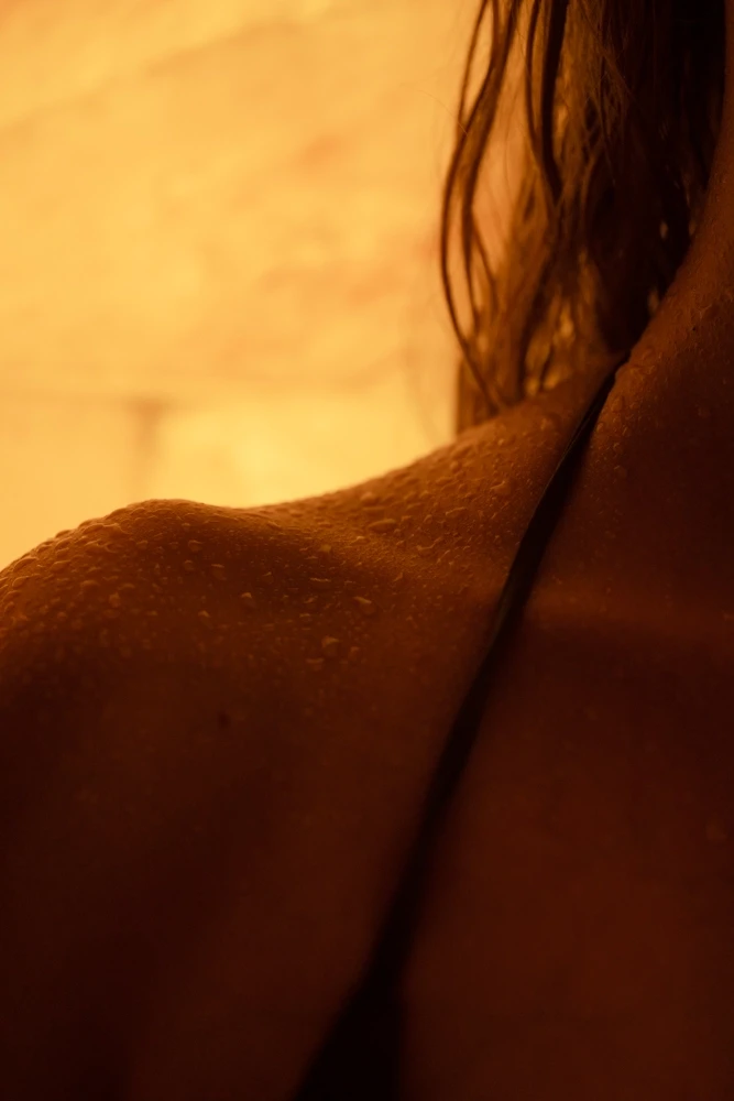 Closeup of body accumulating sweat droplets from heat in Himalayan salt sauna.