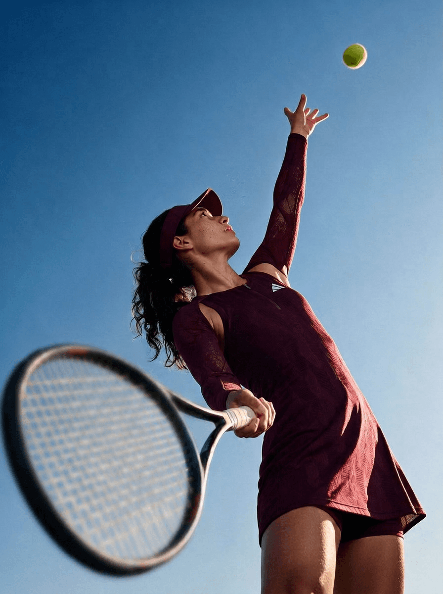 Close-up of the player tossing the ball for a serve against a blue sky