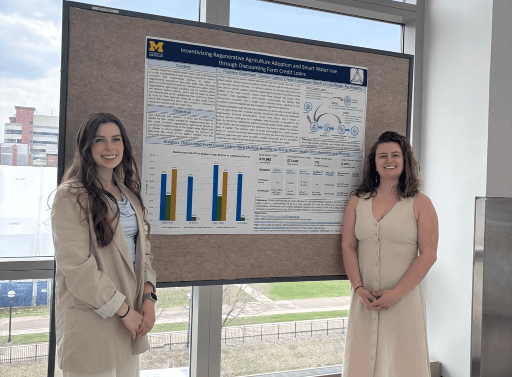 Two women stand next to a poster 