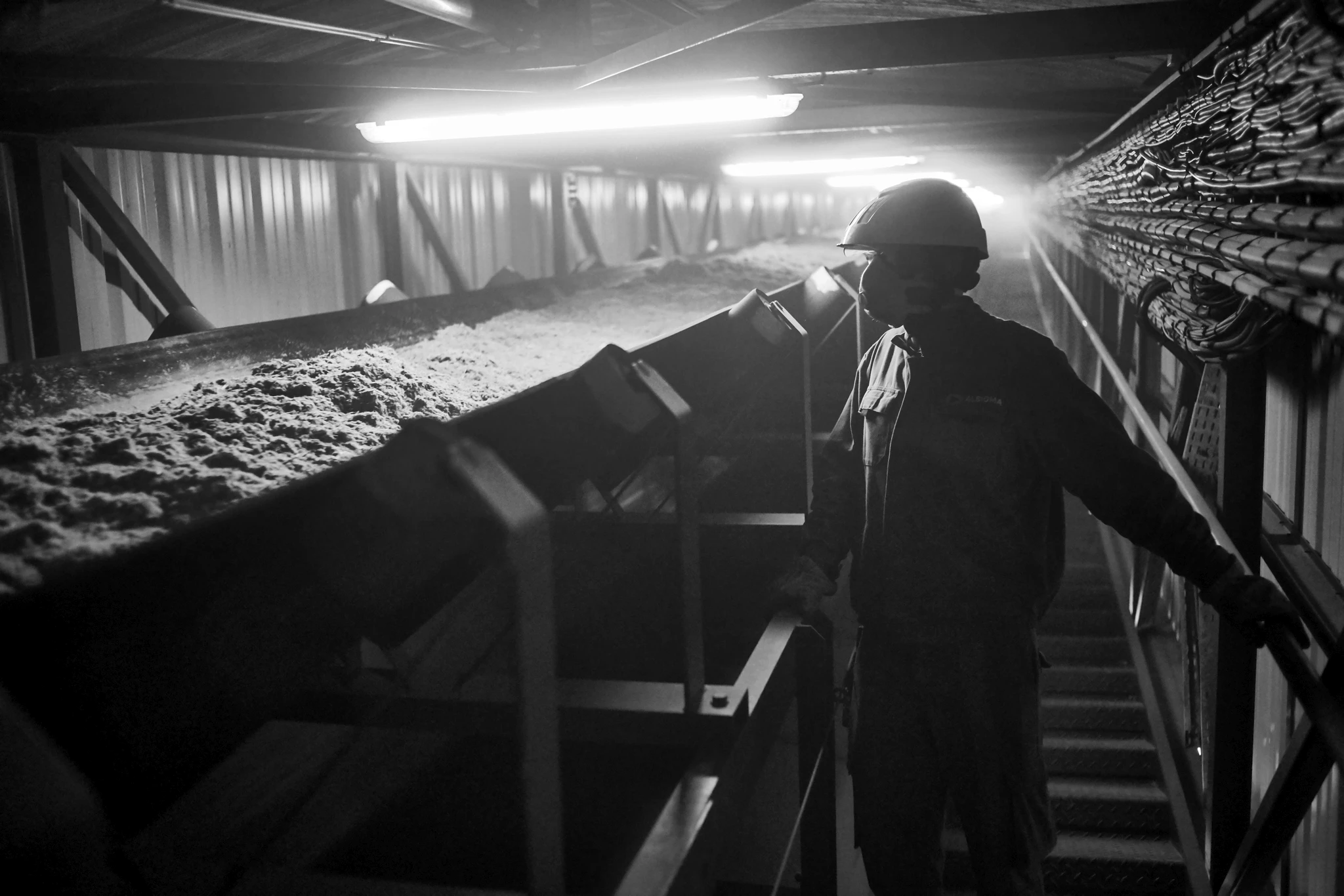 Reportage industriel technique : ouvrier qualifié surveillant un convoyeur de bagasse en usine sucrière à La Réunion — Photographie métier David Dijoux