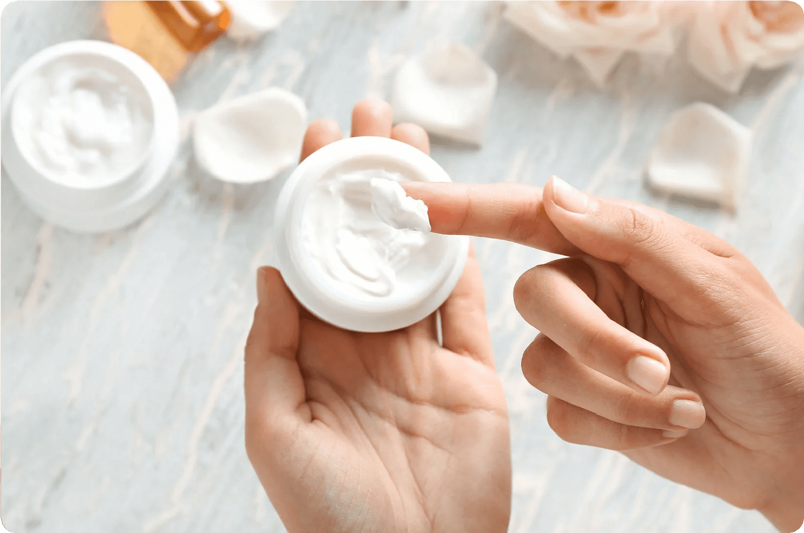 A person touching cream in a white container. Ideal for skincare and beauty.