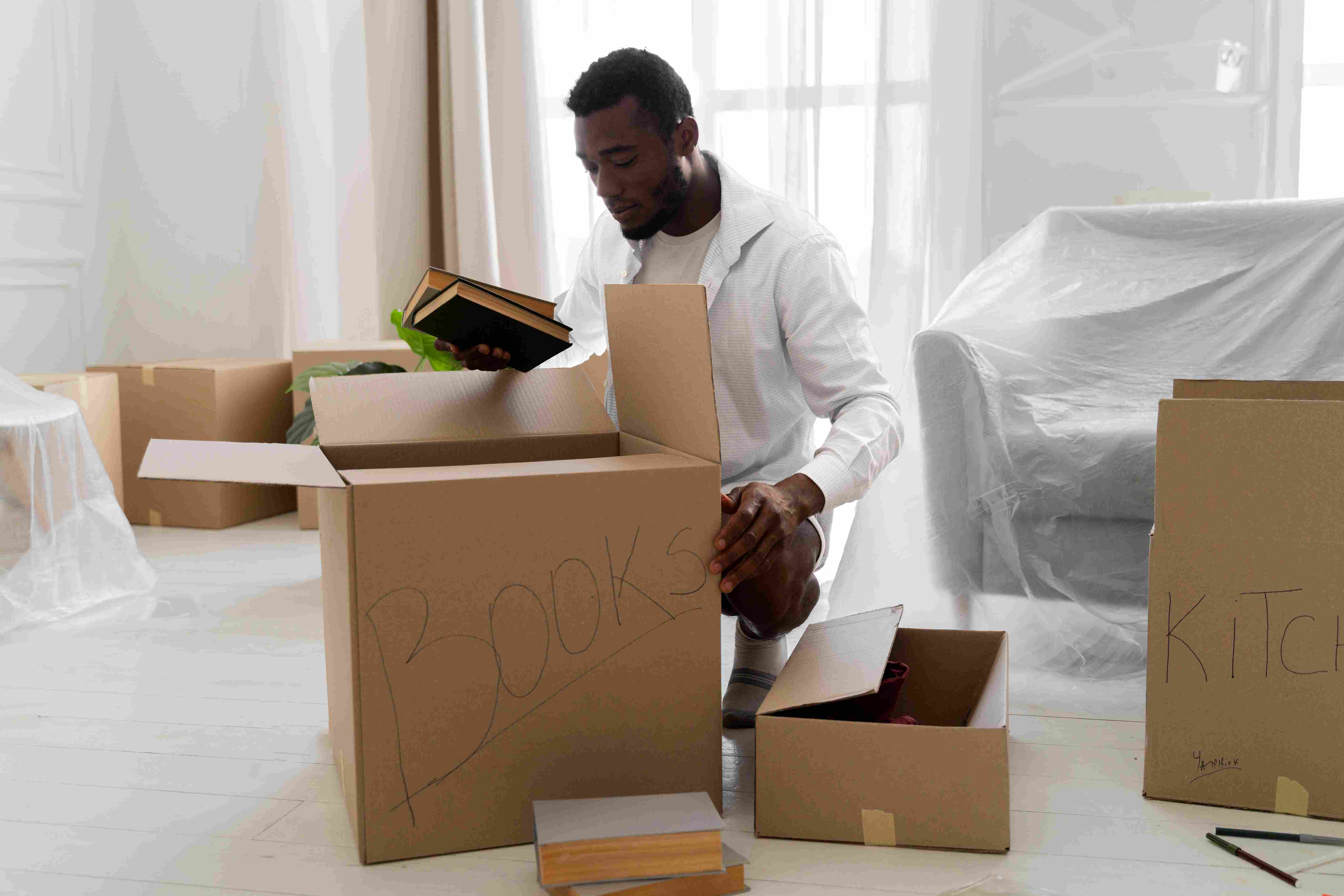 A man packing his things in a well labelled box for a move