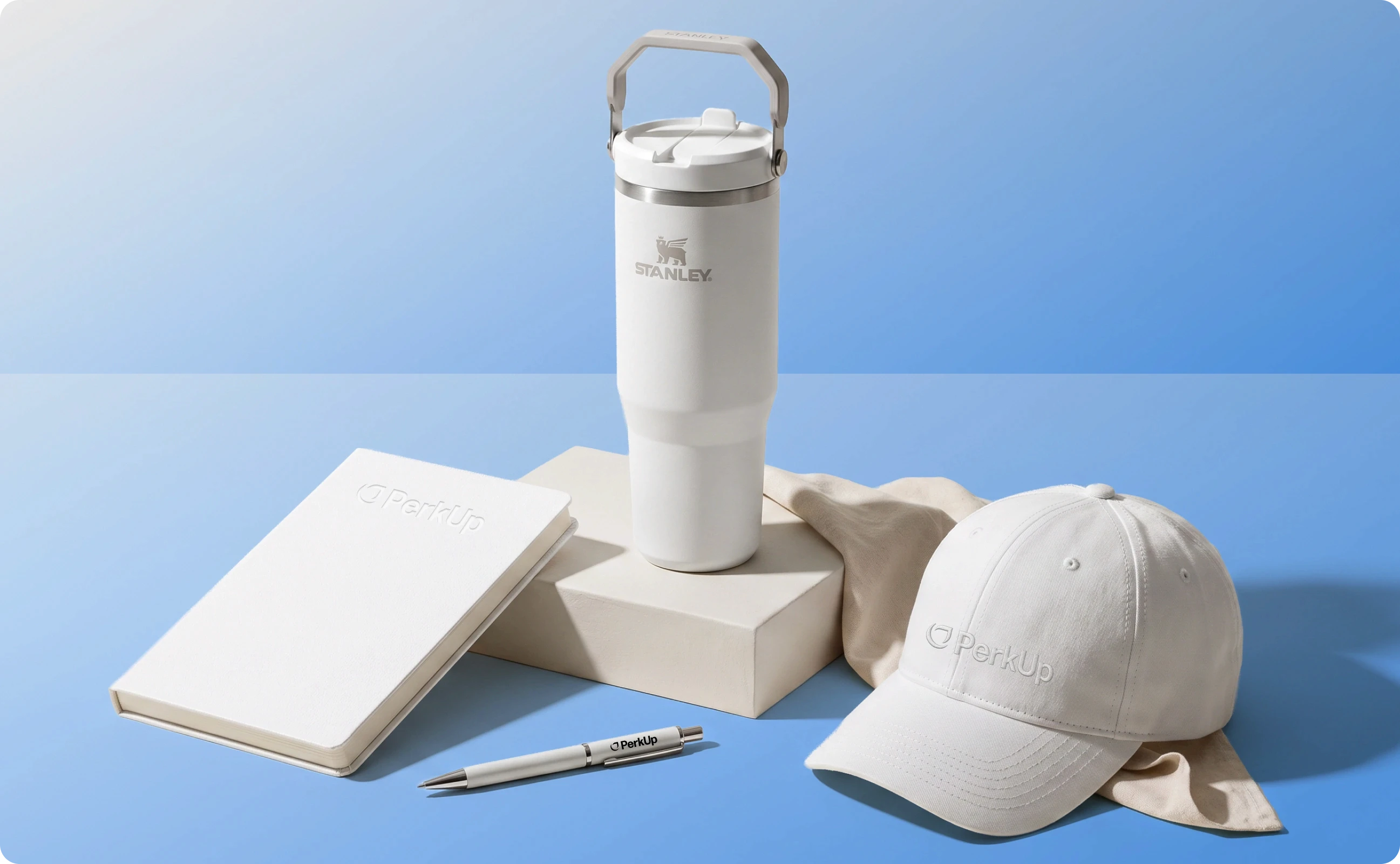 White colored items like a notebook, a pen, a tumbler, a box, a hat, and an apparel item.