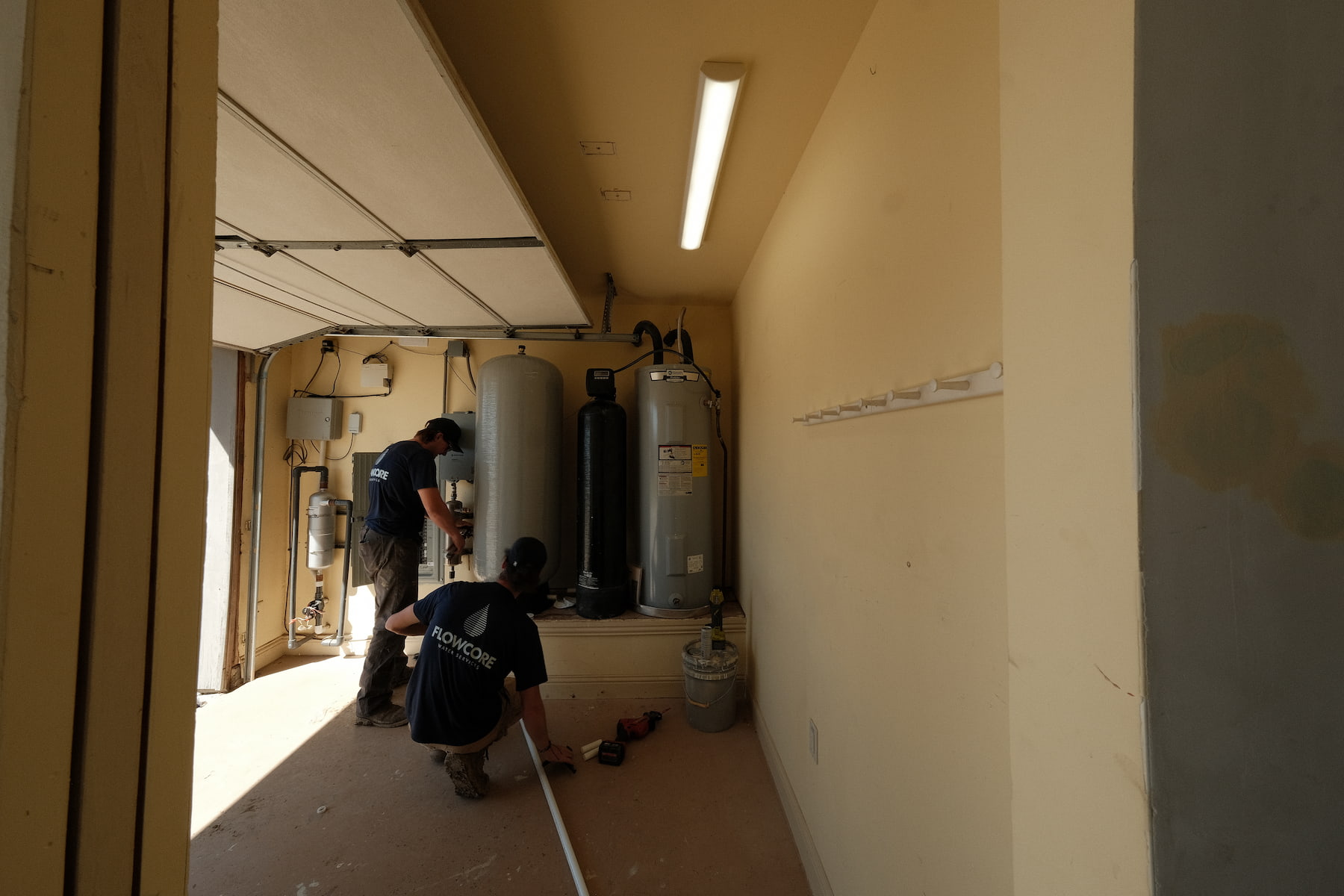 Flowcore Water Services technicians installing a whole-home water treatment and filtration system in a residential garage in North Texas — DFW water softener and well water treatment