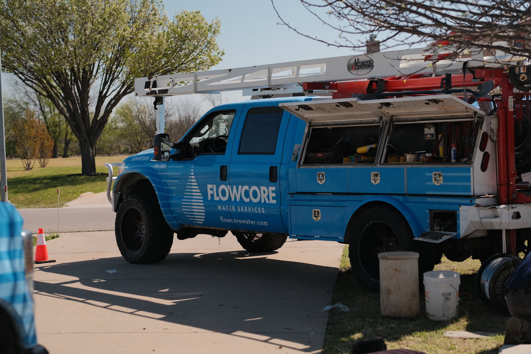 Flowcore Water Services licensed well drilling and pump service truck PU-002 on a residential job site in North Texas — DFW water well services