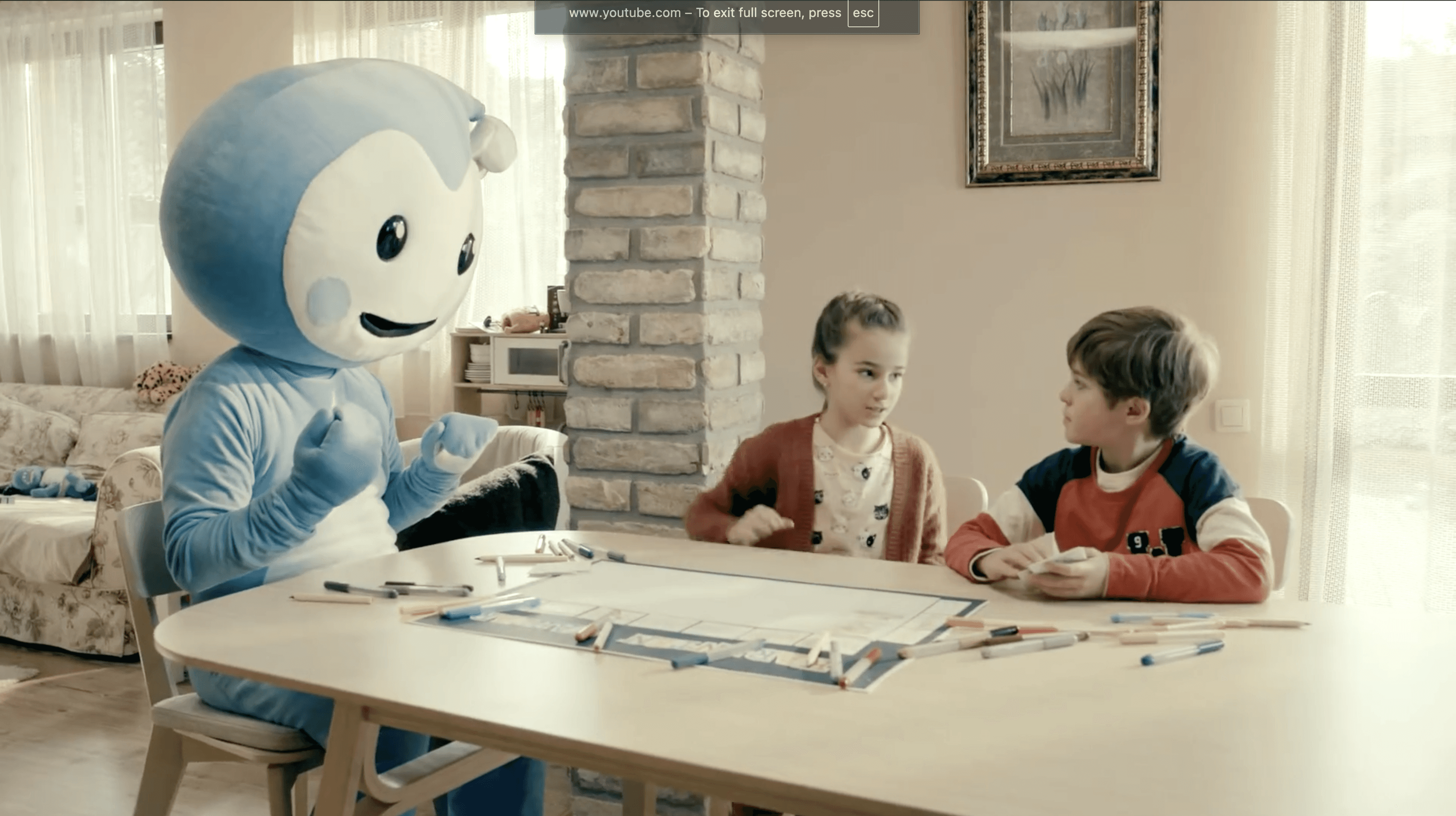 Cseppbarát kék kabalafigurája a asztalnál társasozik a gyerekekkel