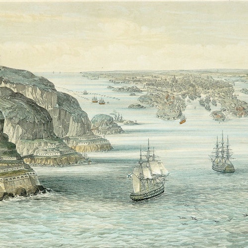 Kuvaus rannikkokaupungista, jonka maisemassa on kallioita, linnoituksia ja lukuisia purjeveneitä vedessä.