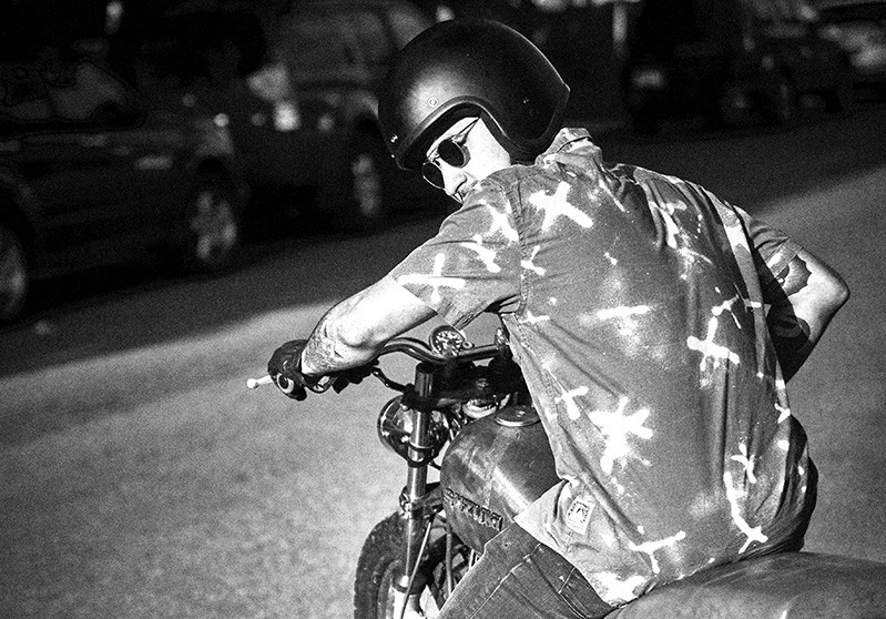 A black and white photo of a man riding a bike.