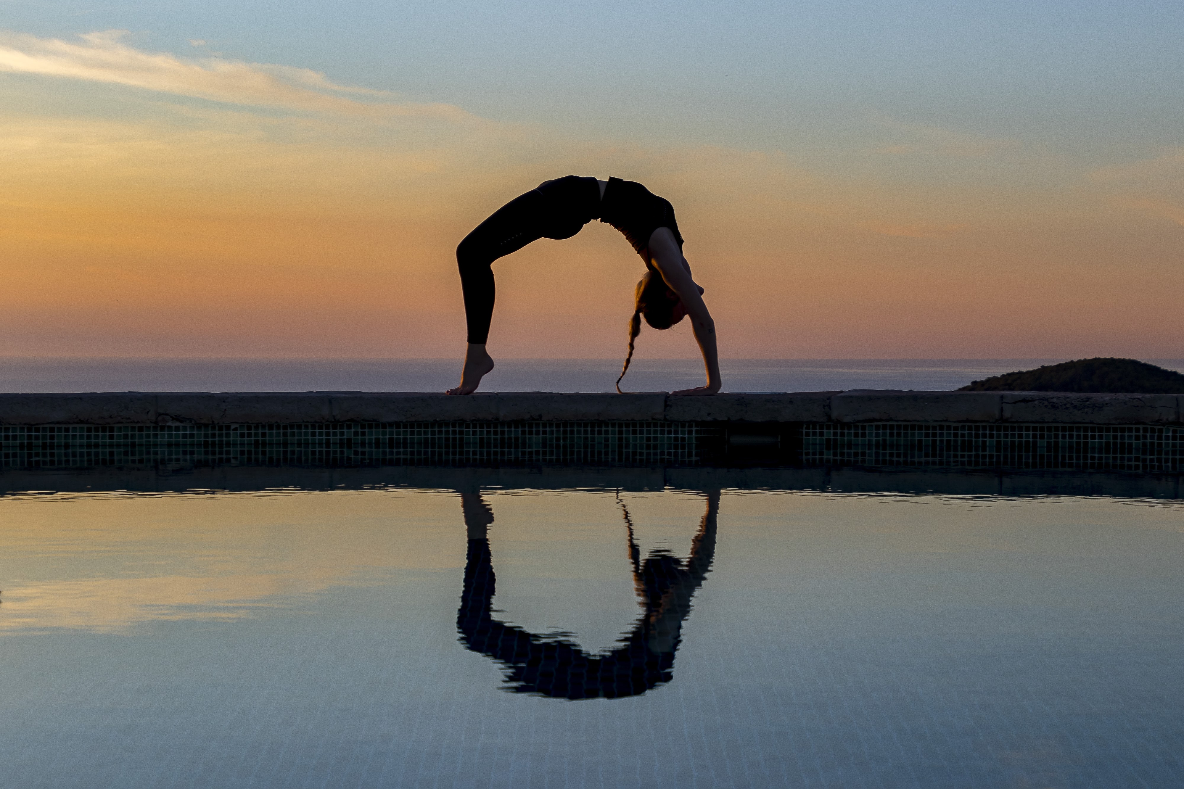 Woman Practicing Yoga with Serene Sunset Pool Reflection