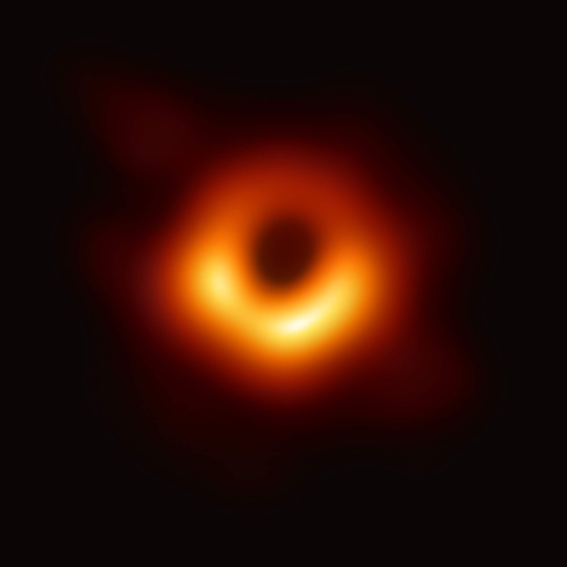 Famous image of a black hole, captured by the Event Horizon Telescope, showing a glowing ring of orange and yellow light surrounding a dark central shadow. The bright halo represents superheated gas and dust orbiting the event horizon, visually confirming the existence of a black hole.