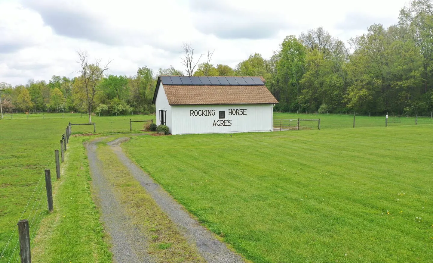 Fenced pasture and white sheep barn with painted farm name at Rocking Horse Acres, Bucks County
