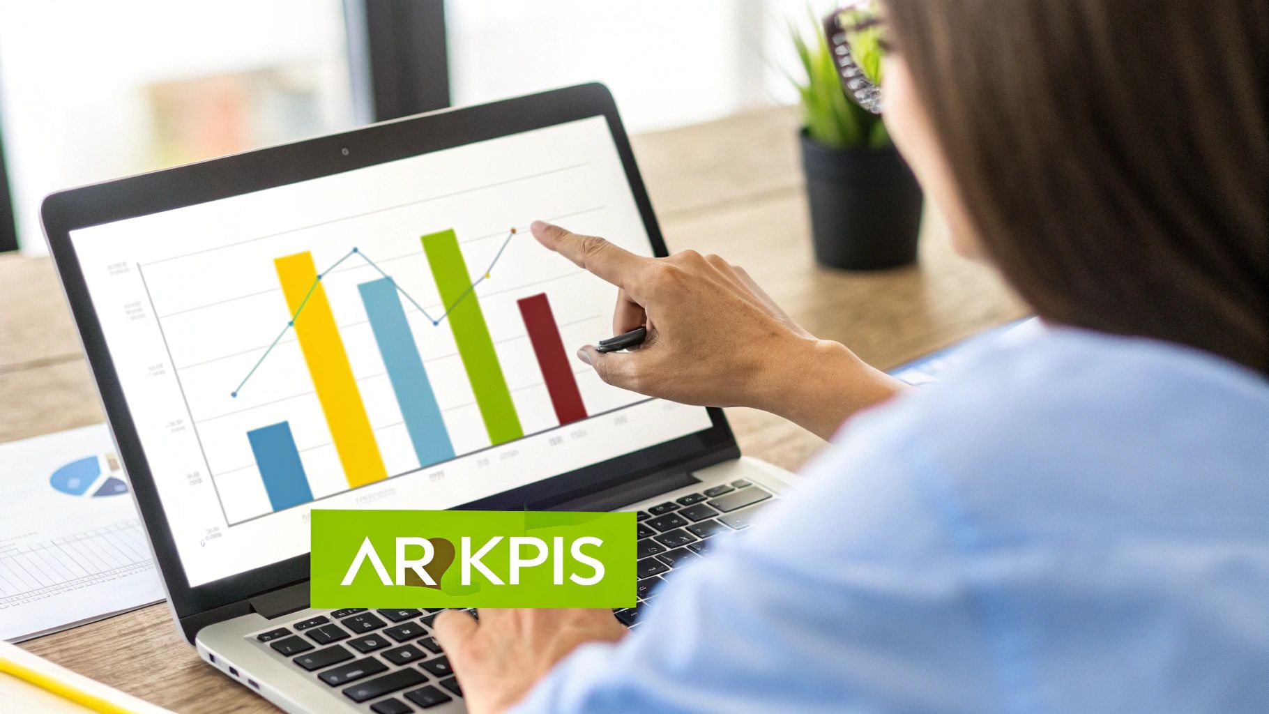 A person's hand points at a laptop screen displaying accounts receivable KPIs and performance graphs.