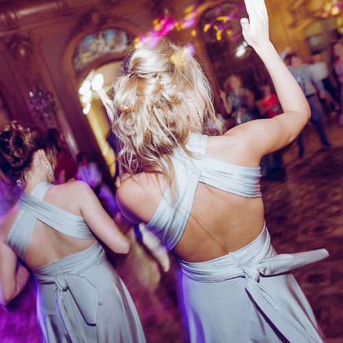 A vibrant wedding reception scene with guests enjoying the night, the dance floor filled with movement, and the room lit in a beautiful array of colorful lights.