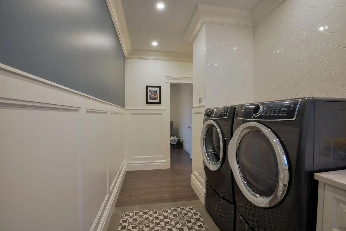 Image of Laundry room with stacked washer and dryer, tile backsplash, and decorative flooring, KHD Homes design.