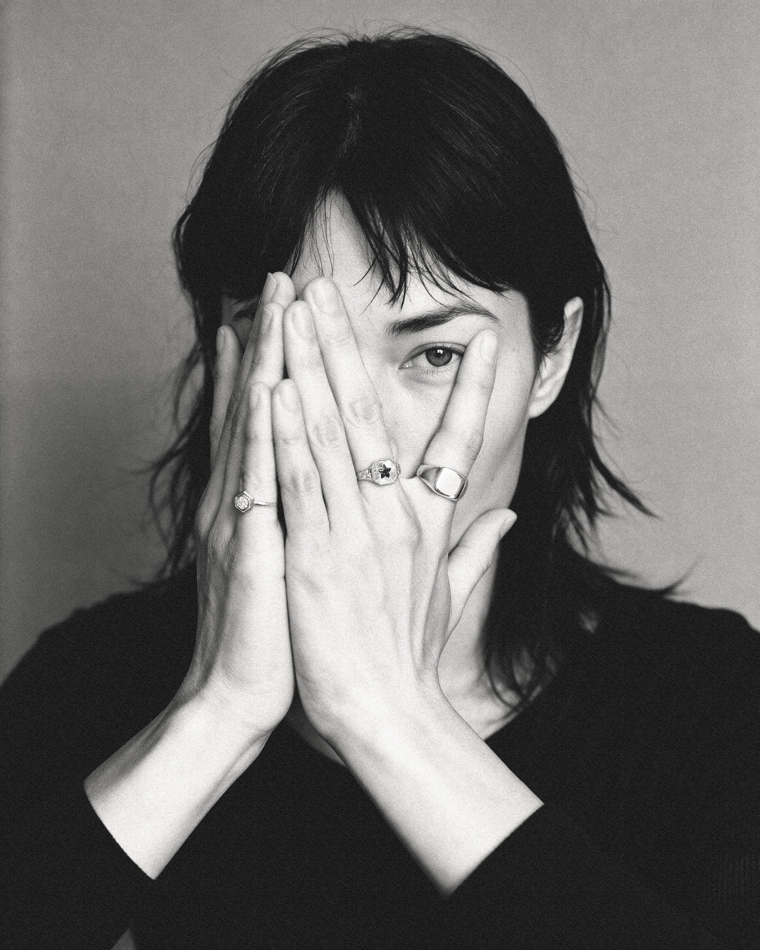 Black-and-white portrait with silver rings framing the face