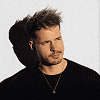 Man with tousled hair in dark sweater.