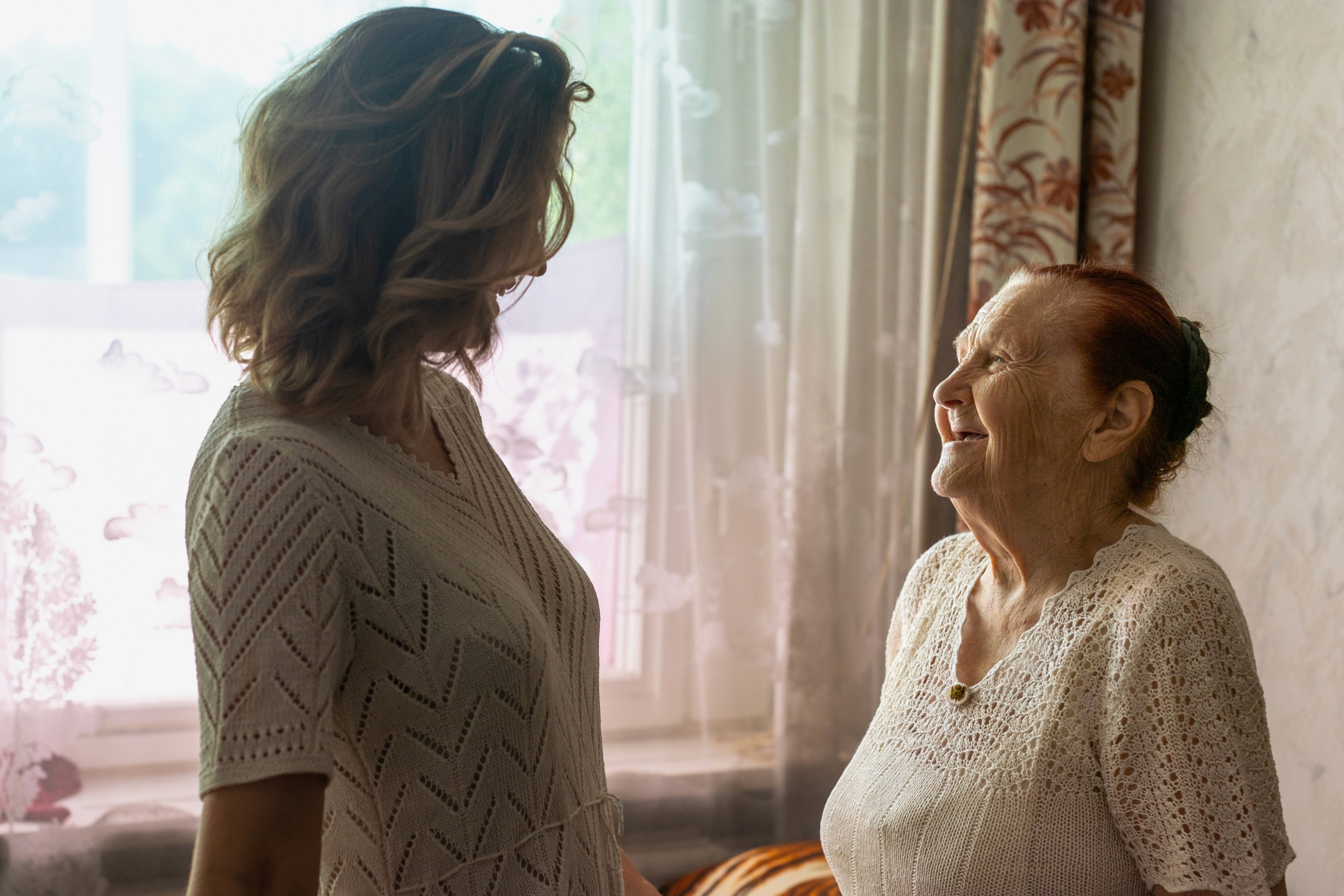 Dwie kobiety, młodsza oraz starsza uśmiechające się do siebie