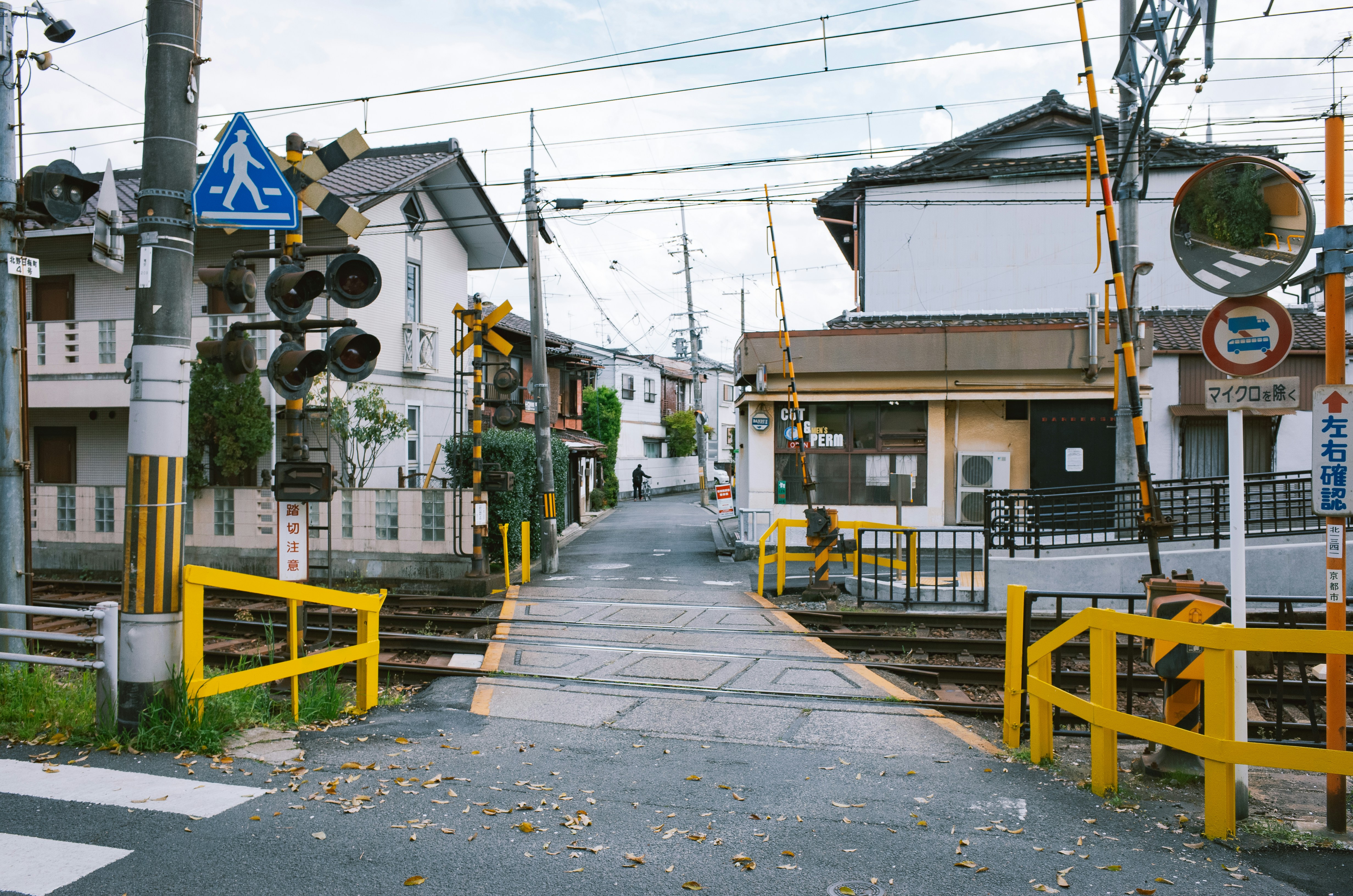 A quiet street with a railway crossing and houses.