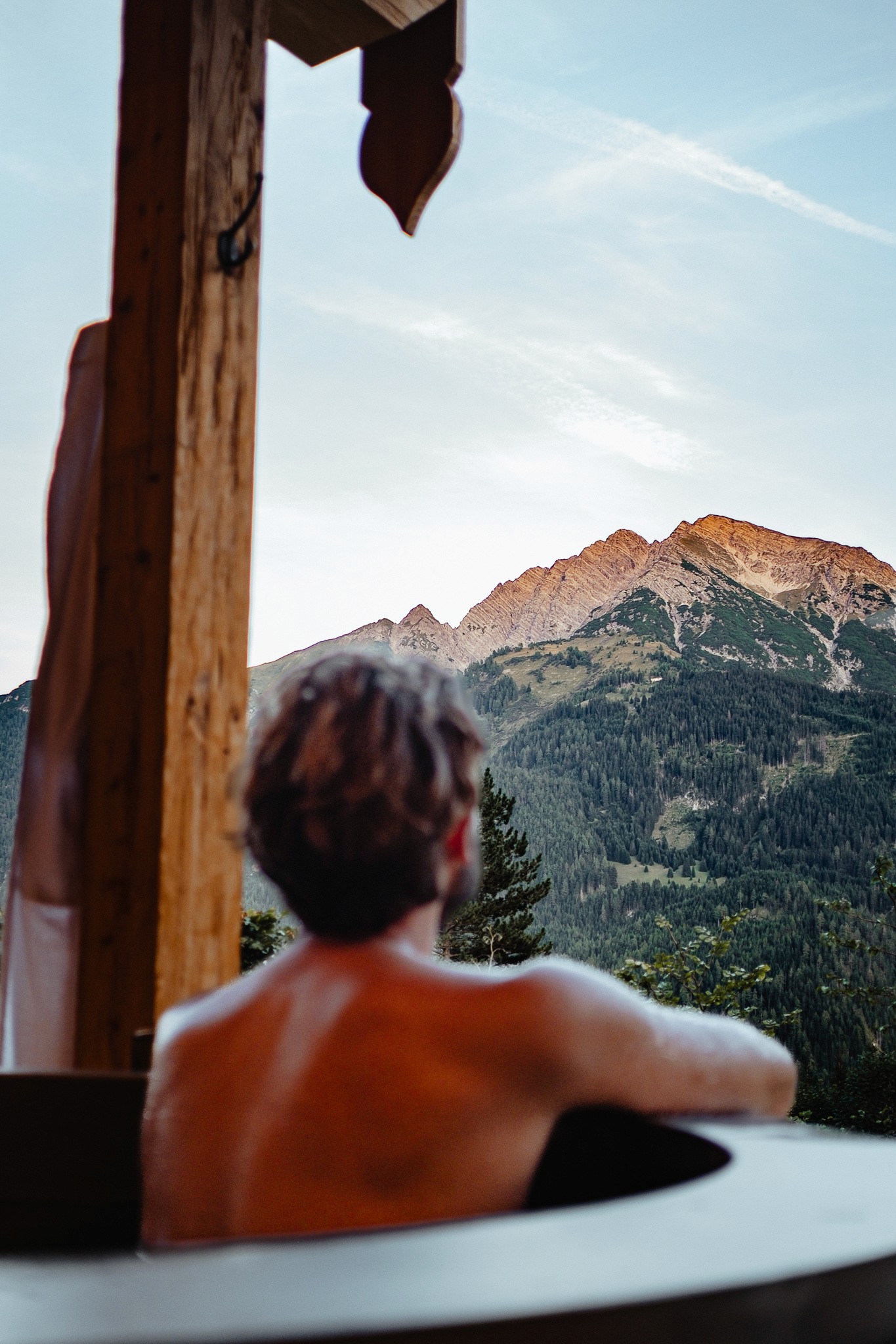 Gast genießt den Ausblick auf die Alpen vom privaten Chalet-Balkon mit Hotpot – Ruhe und Entschleunigung in der Natur