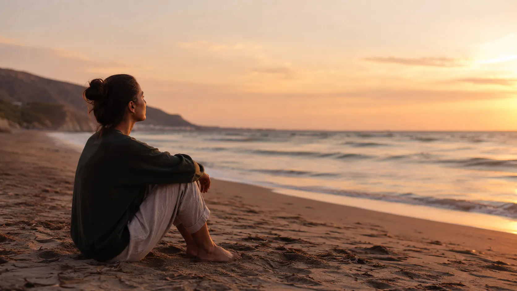 Person sitting on the beach at sunset during quiet post-retreat reflection