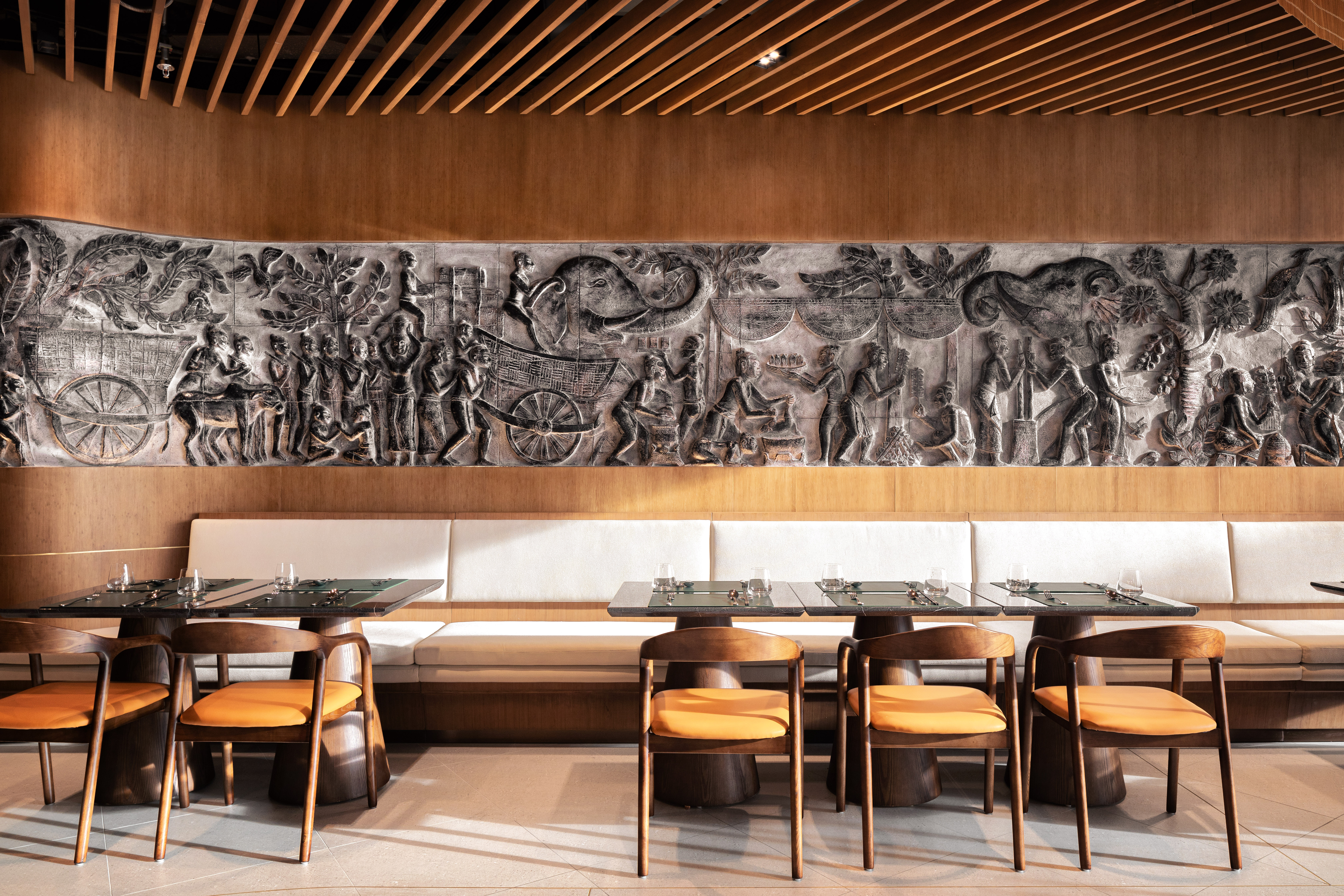 cambodian-khmer-stone-relief-wall Detailed view of a traditional Khmer stone relief carving on a timber-paneled wall inside Malis Restaurant.