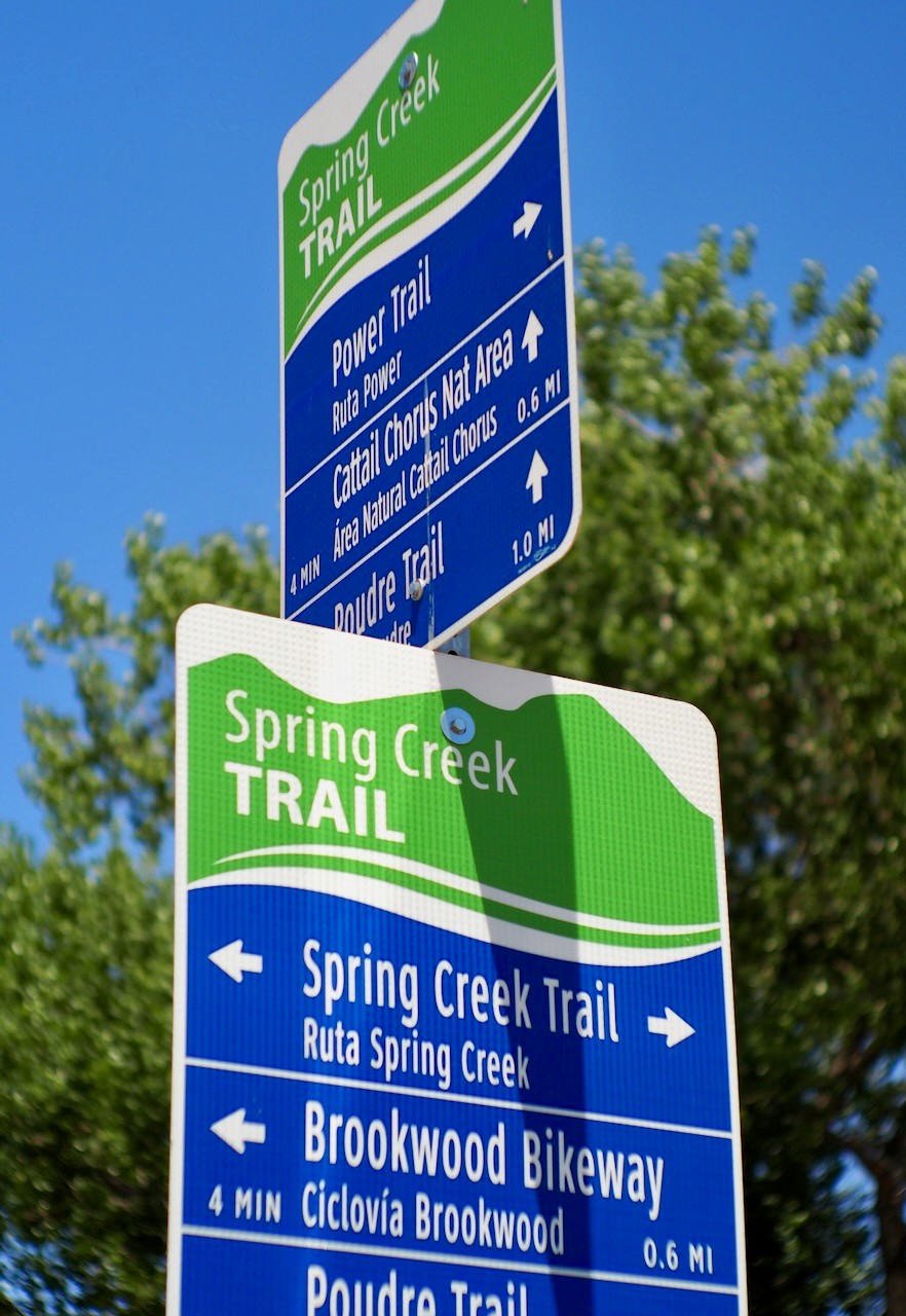 A bike trail marker sign along a path in Mid Town Fort Collins.