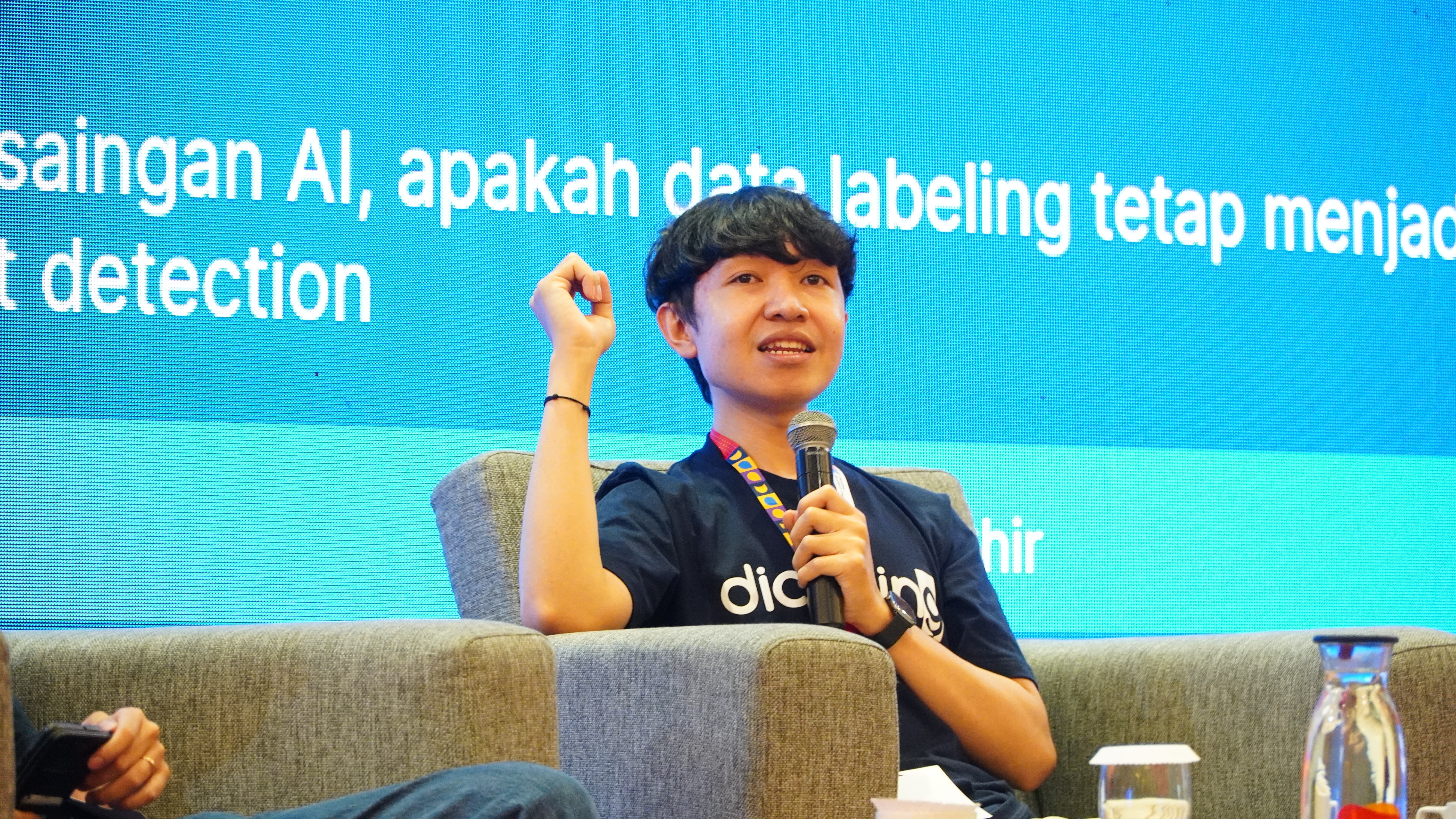 person discussing while standing in front of a large screen in front of people inside dim-lighted room