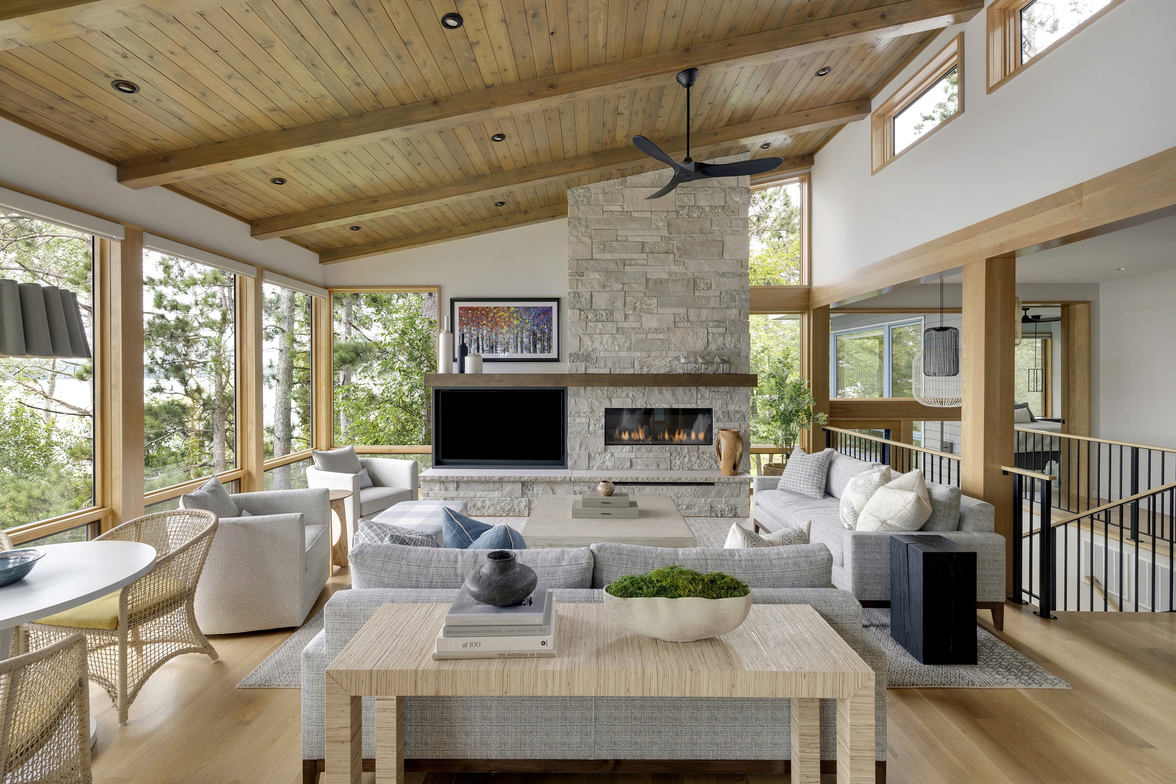 Sand Lake Cabin Charleston - Living area with stone fireplace, vaulted wood ceiling, and open layout by Renae Keller Interior Design