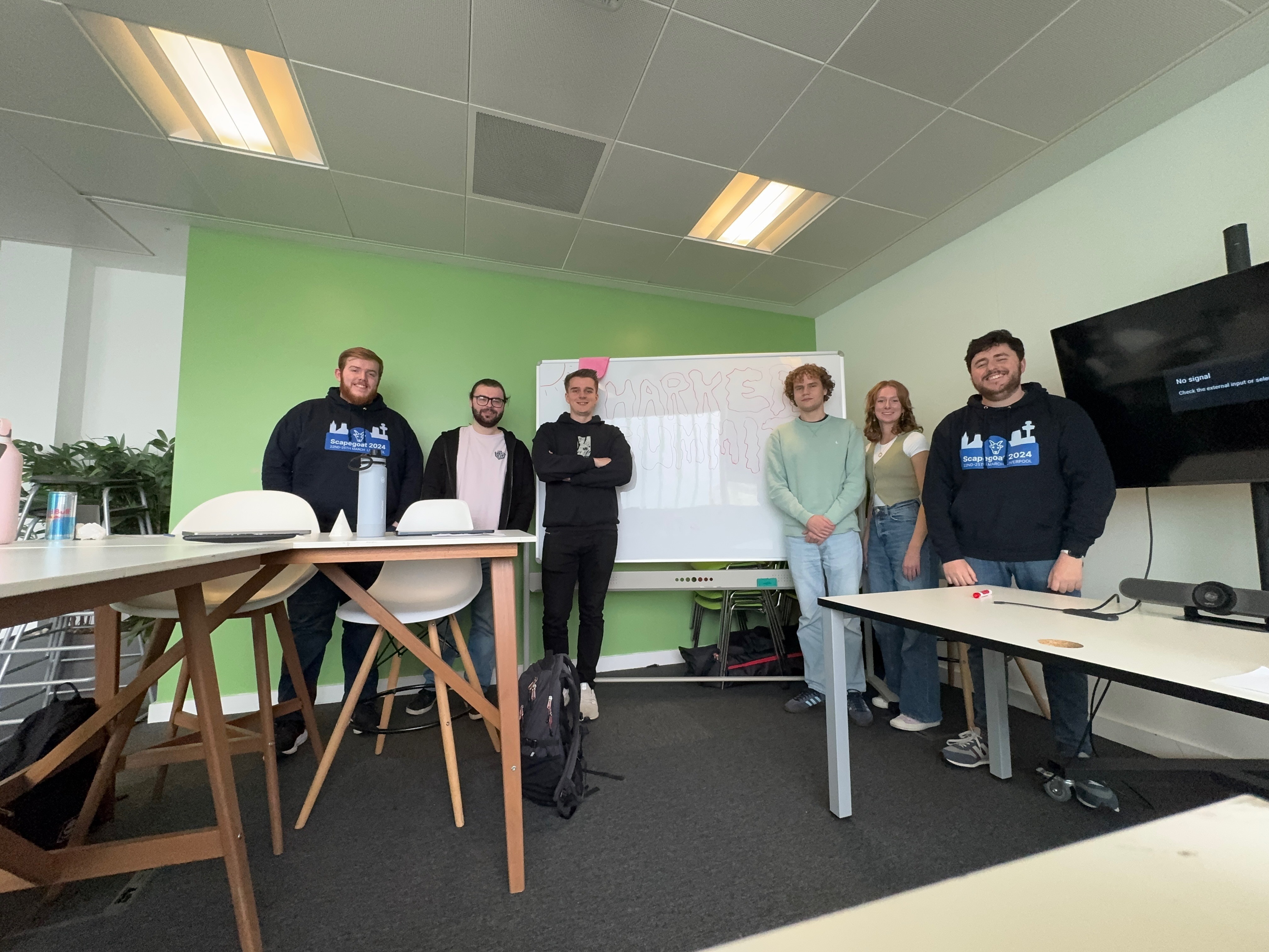 The Harker Team stood together in a meeting room around a whiteboard with large bubble text reading 'HARKER SUMMIT'.