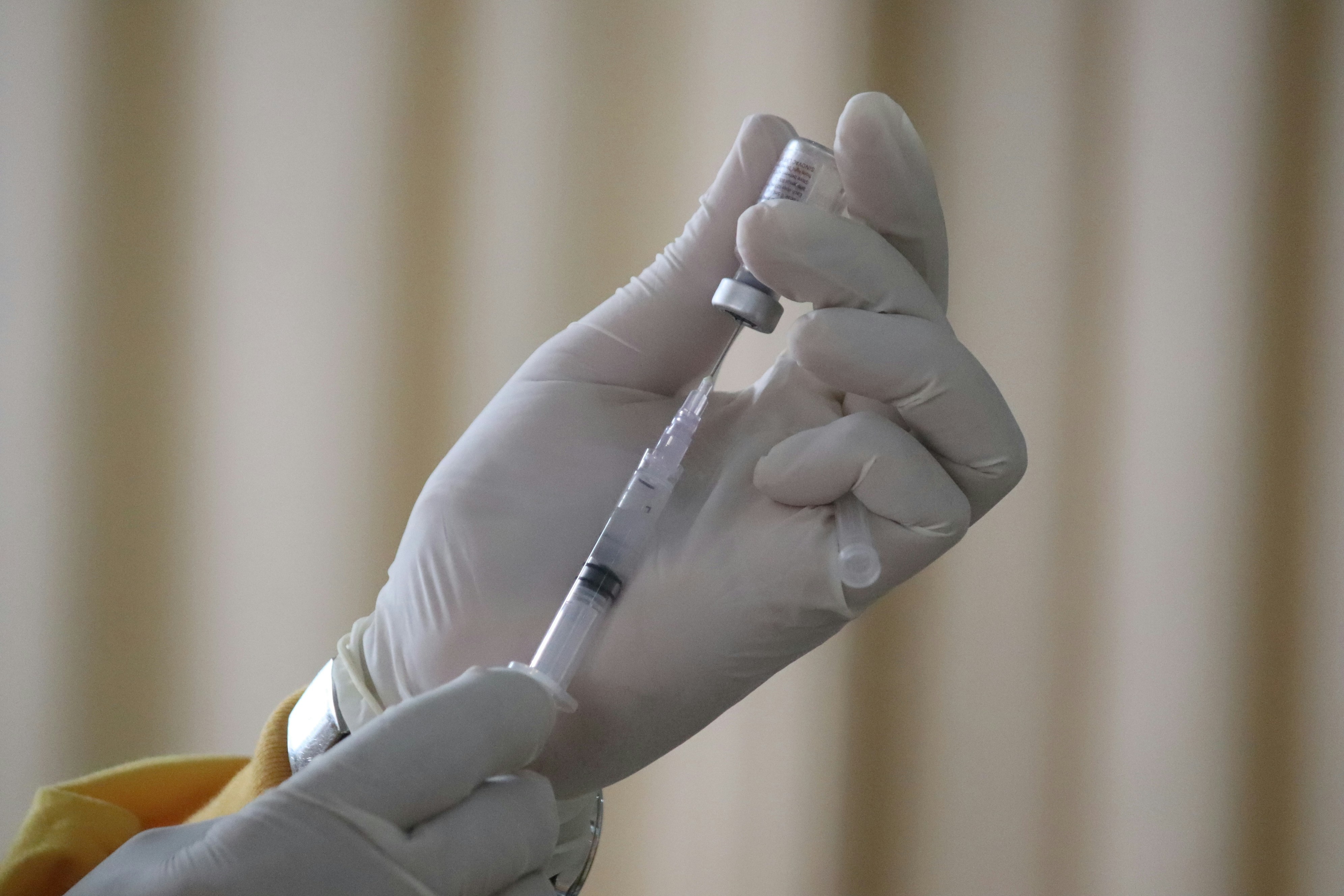 Person in white glove holding vaccine