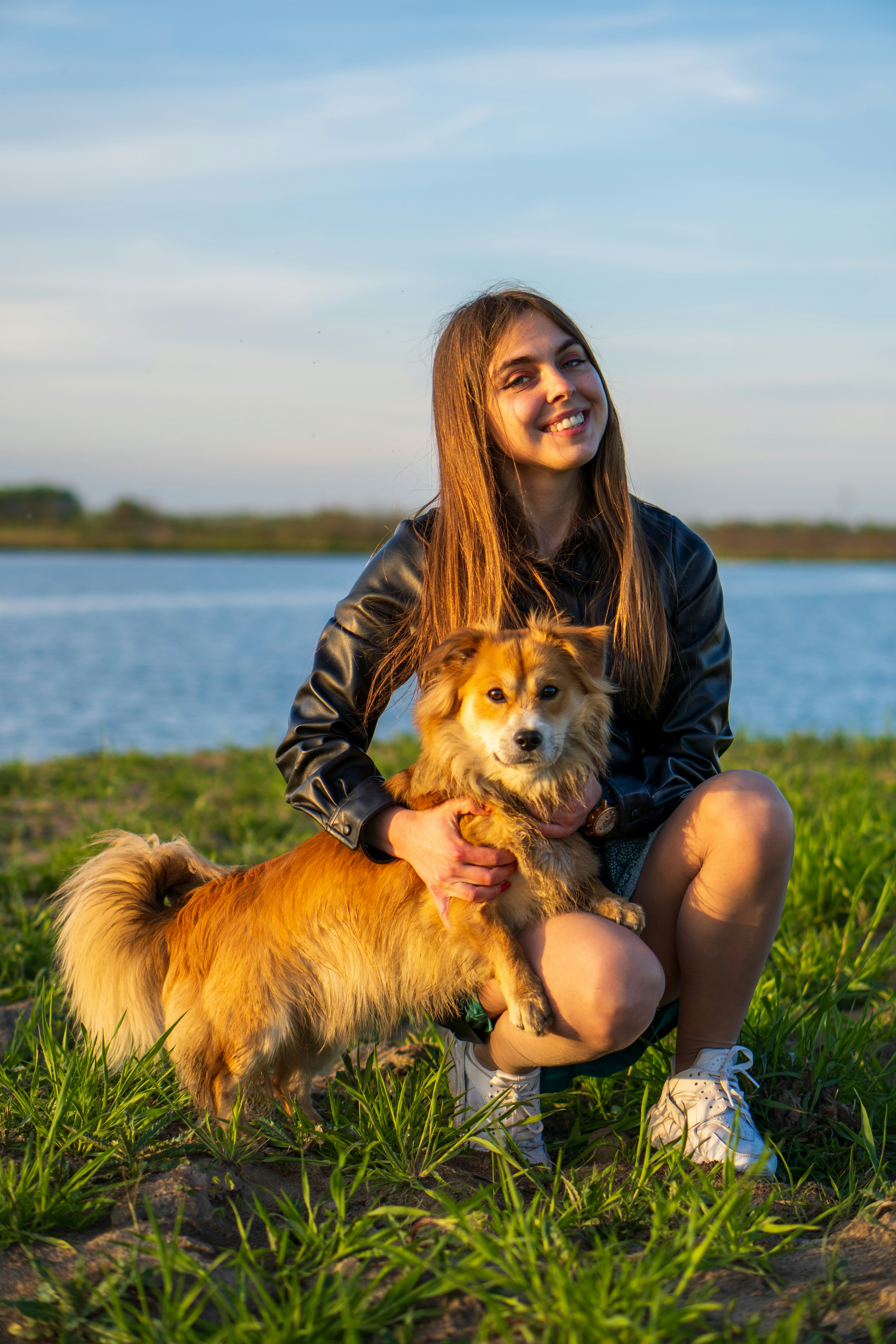 a woman sitting in the grass with her dog