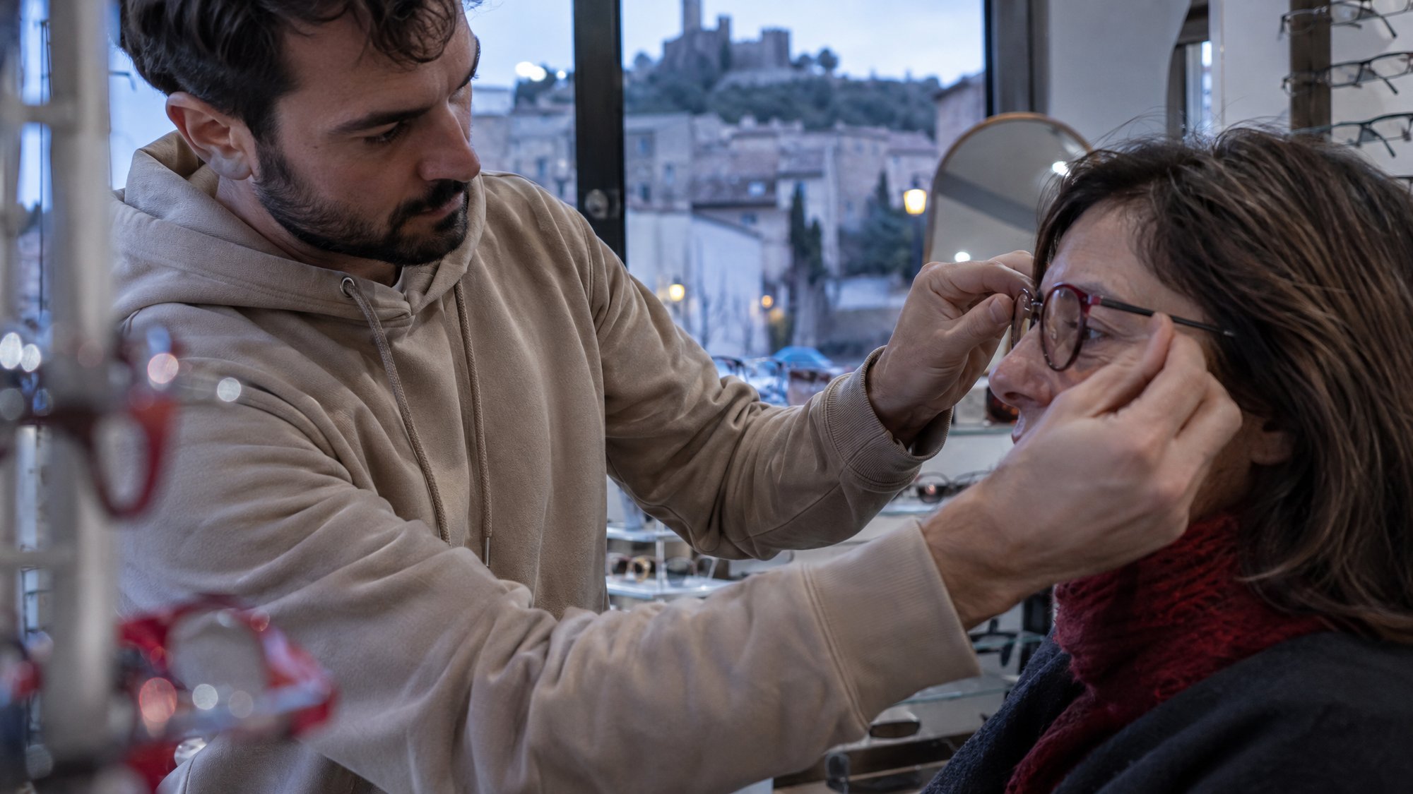 Opticien ajustant une monture sur le visage d'une cliente, dans sa boutique à Clermont-l'Hérault