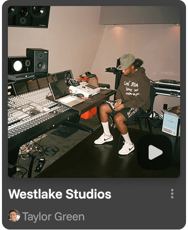 A smiling woman with her arms crossed, standing against a dark green background. She has long, dark hair.