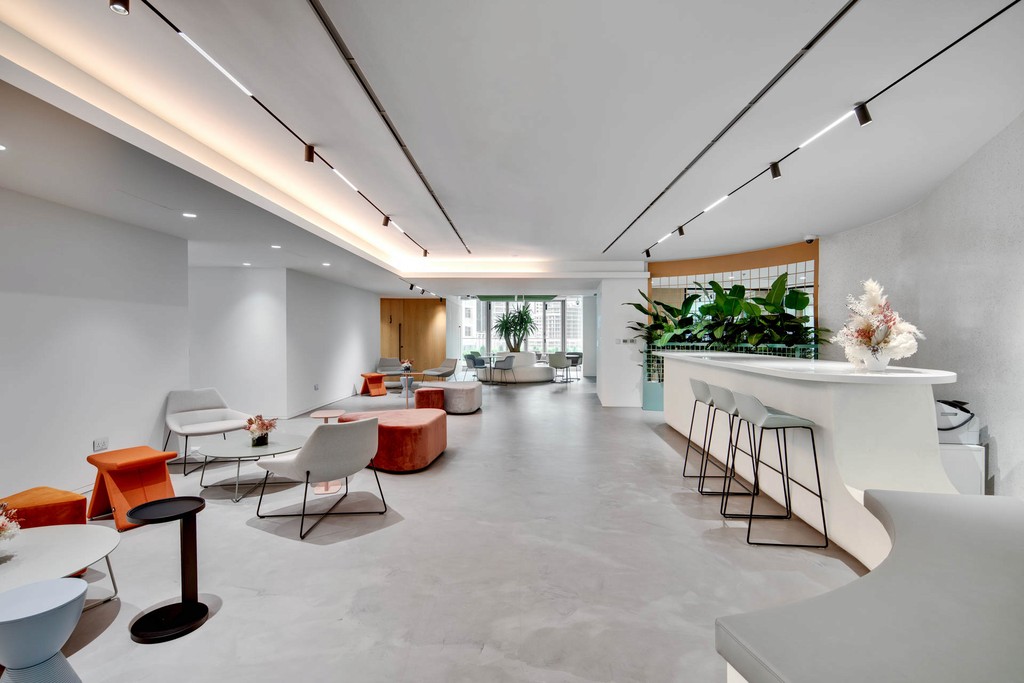 The Binary by Omniyat showcases a contemporary office with a sleek bar and vibrant greenery throughout.
