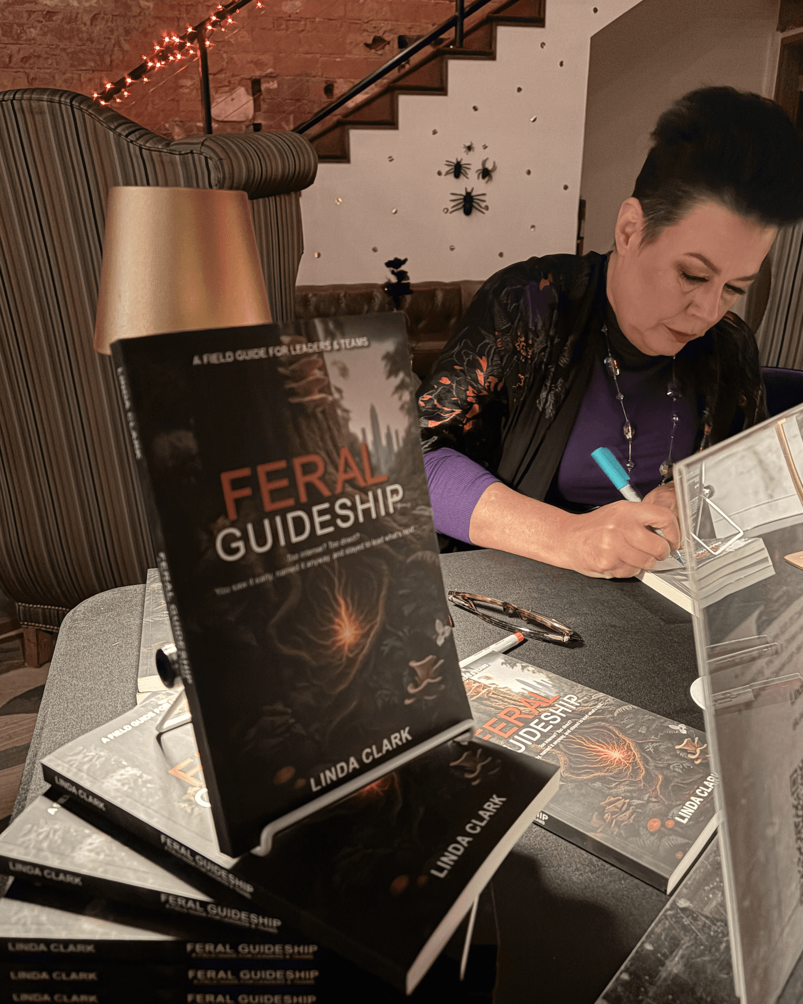 A photo of Linda Clark signing the book, Feral Guideship, at the book launch at the restored distillery, Woodworks, in Edmond, Oklahoma.