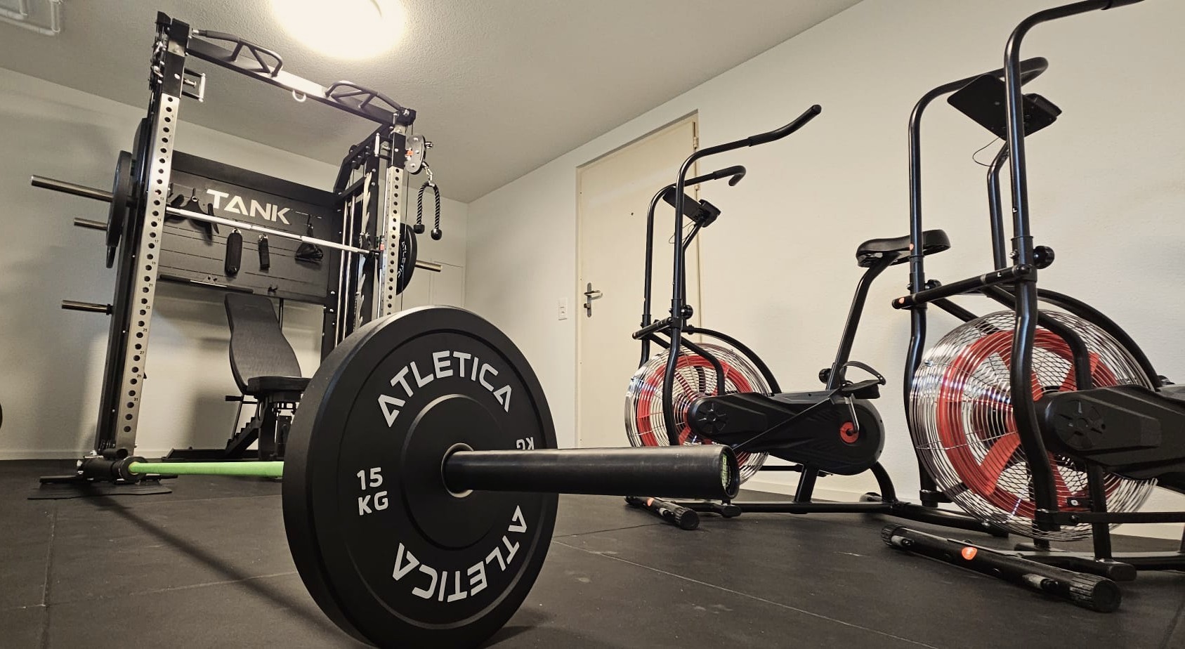 Hell beleuchteter Fitnessraum im Haus Raphael mit Heimtrainern, Hanteln und Gymnastikmatten zur Förderung der körperlichen Gesundheit.