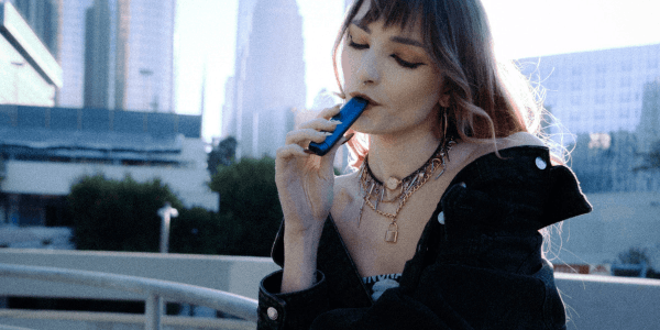 person using iven dry herb vaporizer on a bridge