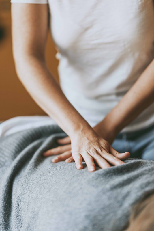 Gros plan sur les mains d’un chiropracteur effectuant un ajustement manuel sur le dos d’une patiente, utilisant des techniques de pression pour améliorer l’alignement de la colonne vertébrale et soulager les douleurs.