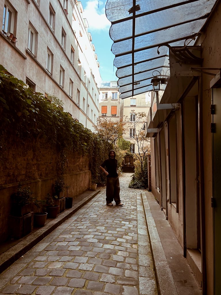 A thoughtful young person with dark hair gazes to the side, captured in soft black and white lighting.