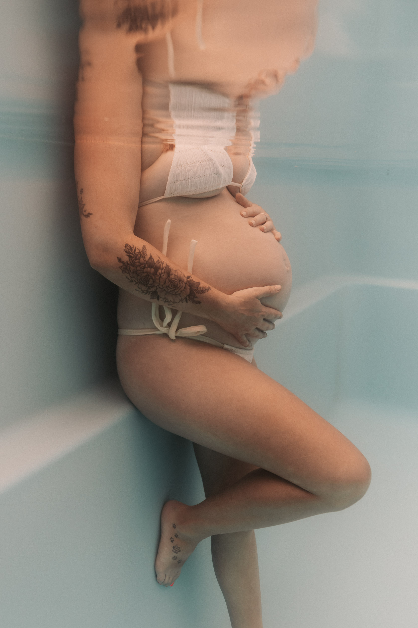Expectant mother submerged gracefully in a clear pool creating artistic underwater pregnancy portraits in Mackay