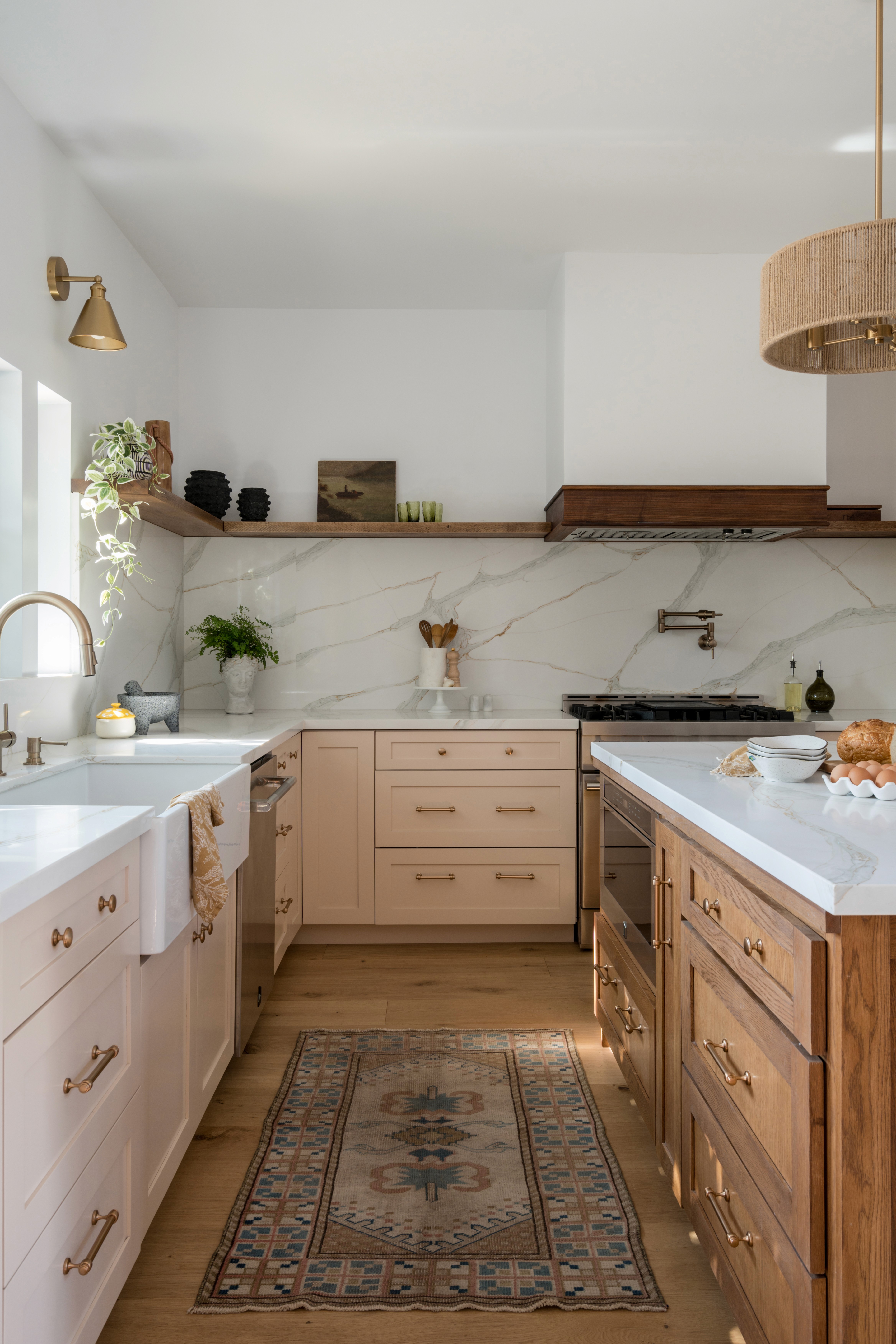 A bright and feminine kitchen featuring white countertops, soft pastel accents, and modern cabinetry. The space is designed with clean lines, a central island for gathering, and plenty of light, creating an inviting atmosphere by Jubilee Interiors in Lakewood, California