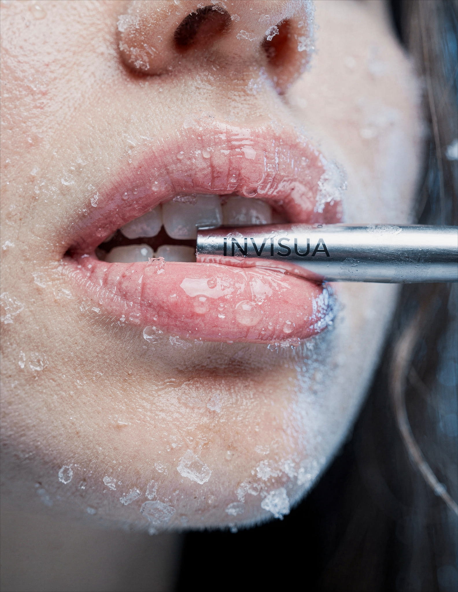 a person's mouth and nose, covered in ice crystals and water droplets. The lips are slightly parted, revealing teeth and a silver tube