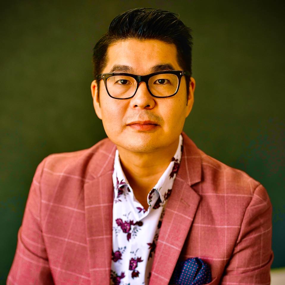 woman in black blazer covering her face with her hand